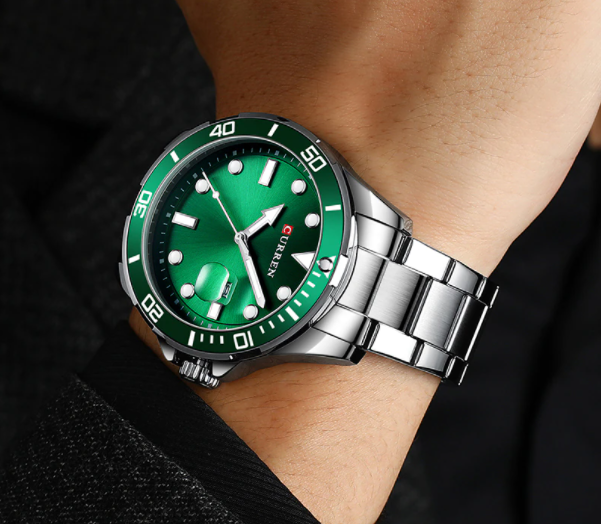 Green watch with silver strap on a wrist against a dark background