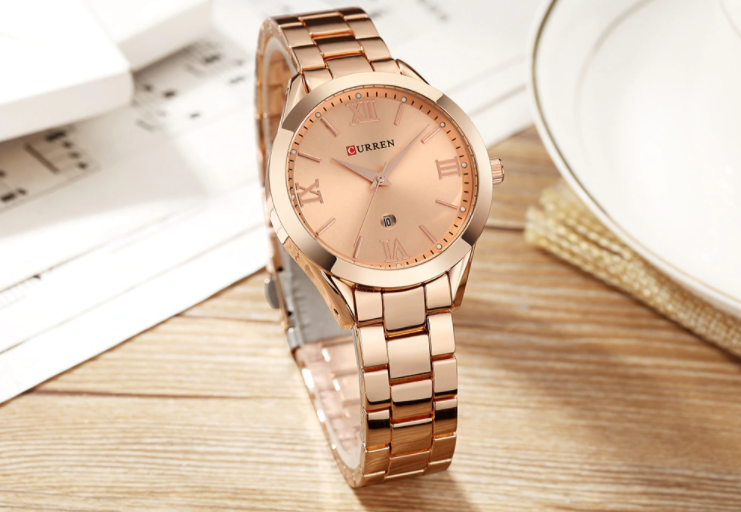 Rose gold watch with a metallic band on a wooden surface